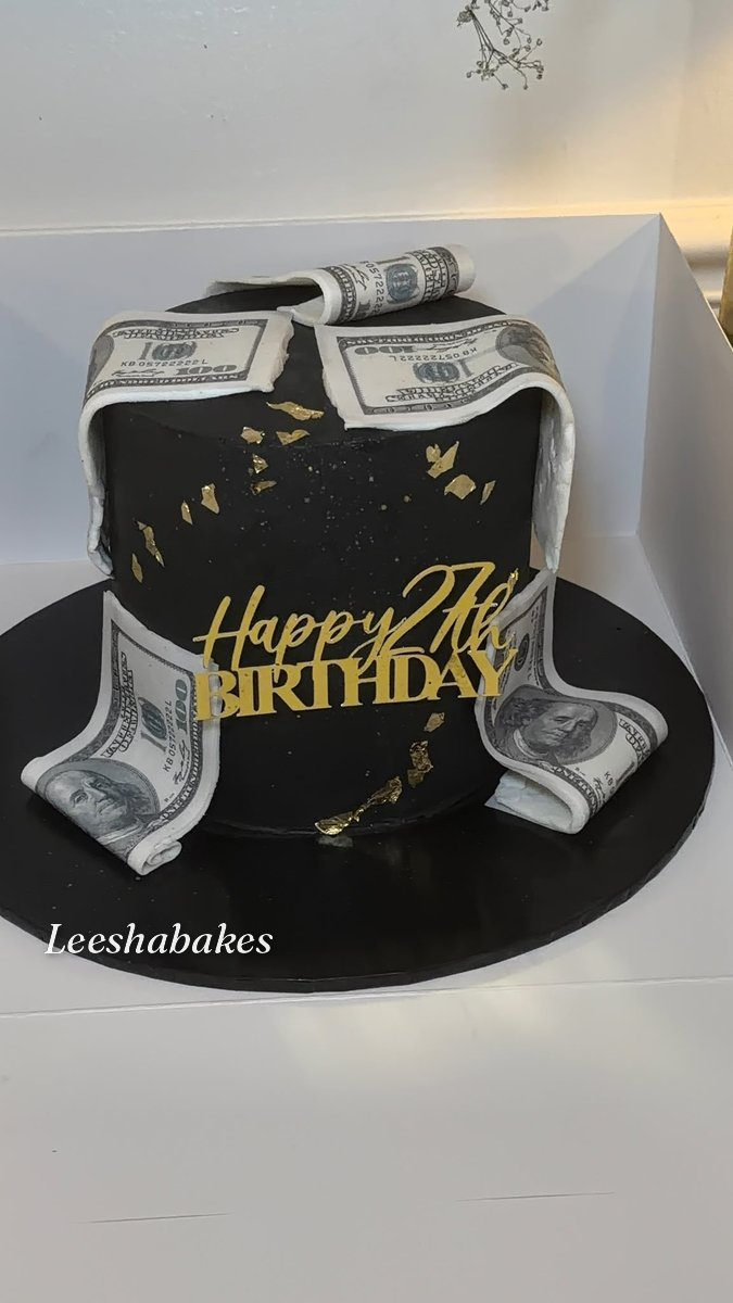 Black cake with edible $100 dollar bills, gold leaf and 'Happy 27th Birthday' topper