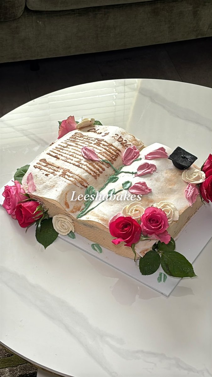 Open book cake with fresh pink and red roses and a graduation cap for Class of 2026