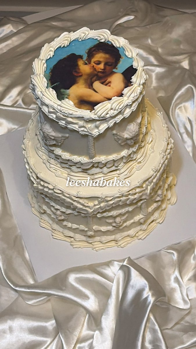 White tiered vintage cake with piped scrolls and an edible classical portrait on top