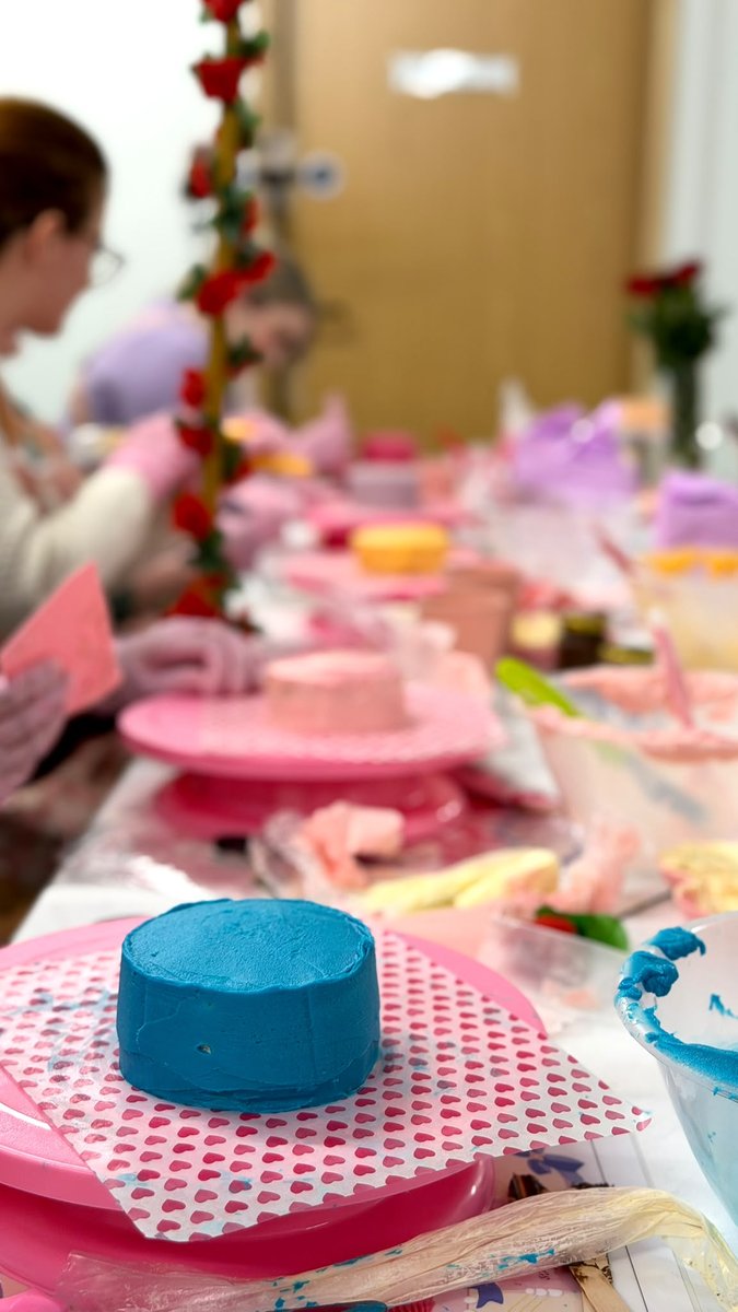 A small bento cake iced in blue on a turntable at the workshop table